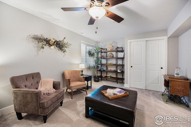 sitting room featuring baseboards, a ceiling fan, visible vents, and light colored carpet