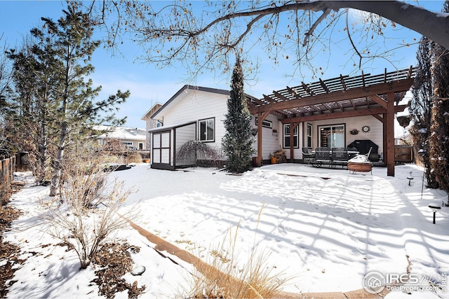 snow covered house with an outbuilding, a storage unit, and fence