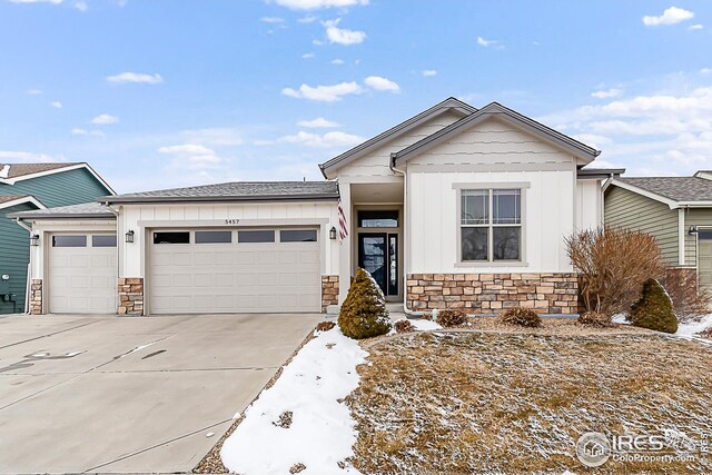 view of front of house featuring driveway, stone siding, board and batten siding, and a garage