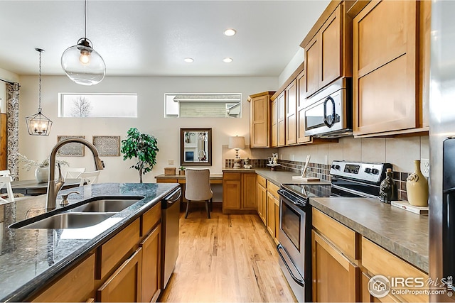 kitchen featuring brown cabinets, a sink, pendant lighting, light wood-style floors, and stainless steel appliances