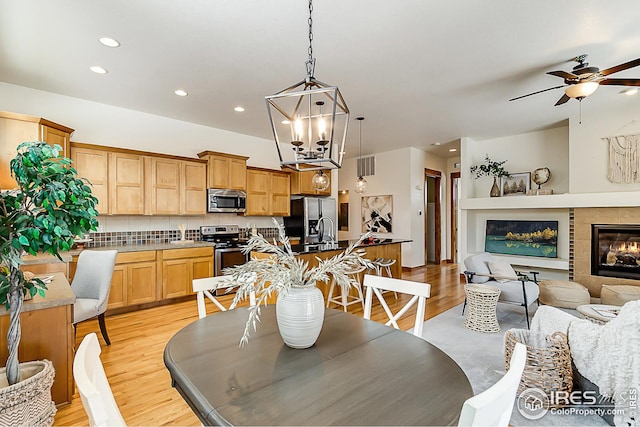 dining room with a glass covered fireplace, visible vents, recessed lighting, ceiling fan, and light wood finished floors