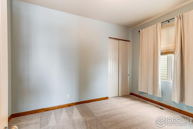 carpeted spare room featuring baseboards and visible vents