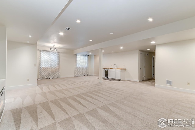 basement featuring light carpet, baseboards, visible vents, recessed lighting, and a sink