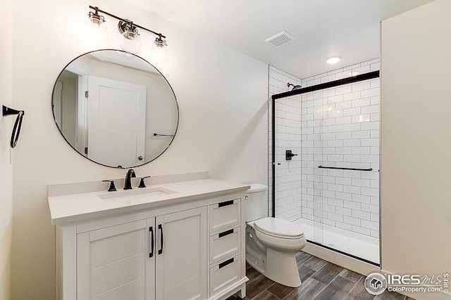 full bath featuring a stall shower, visible vents, vanity, and wood finished floors