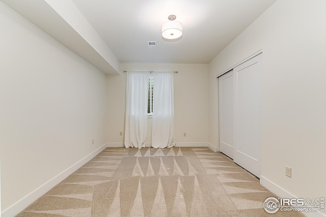 unfurnished room featuring baseboards, visible vents, and light colored carpet