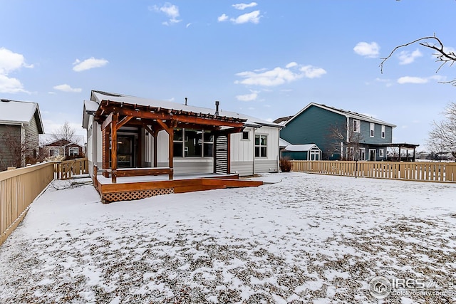 snow covered property with fence and board and batten siding