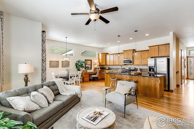 living room featuring a ceiling fan, recessed lighting, and light wood-type flooring