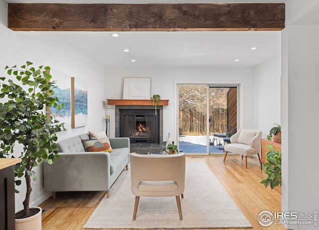 living area with a tiled fireplace, recessed lighting, and wood finished floors