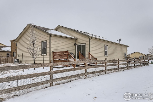 snow covered back of property with cooling unit and fence