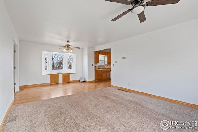 24525 County Road 53, Kersey, CO 80644 - unfurnished room with light colored carpet, a sink, visible vents, baseboards, and light wood-style floors