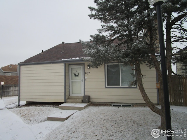 view of front of house featuring a shingled roof and fence