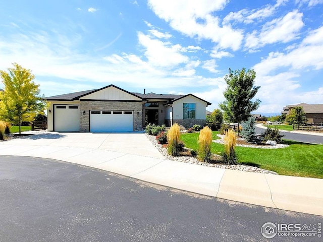 view of front of property with concrete driveway, a front yard, a garage, and stone siding