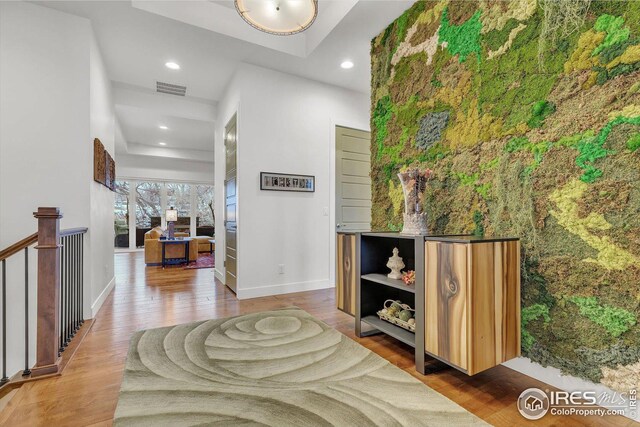 hallway featuring baseboards, visible vents, wood finished floors, and recessed lighting