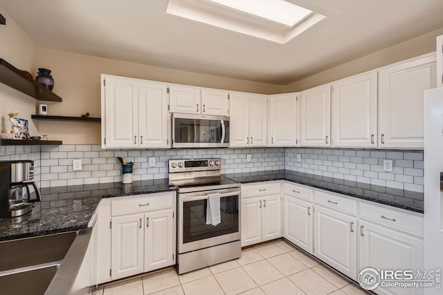 kitchen with light tile patterned floors, tasteful backsplash, white cabinets, appliances with stainless steel finishes, and open shelves