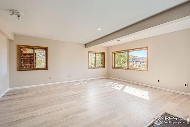 spare room featuring light wood finished floors, baseboards, beam ceiling, and recessed lighting