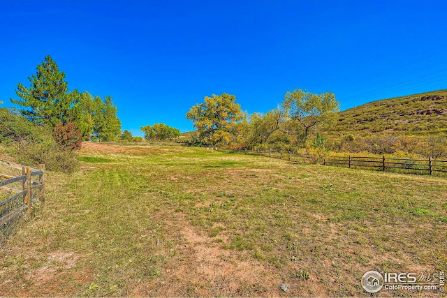 view of yard with a rural view and fence