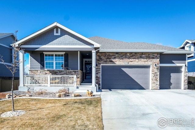 view of front of home with a garage, concrete driveway, stone siding, a porch, and a front yard