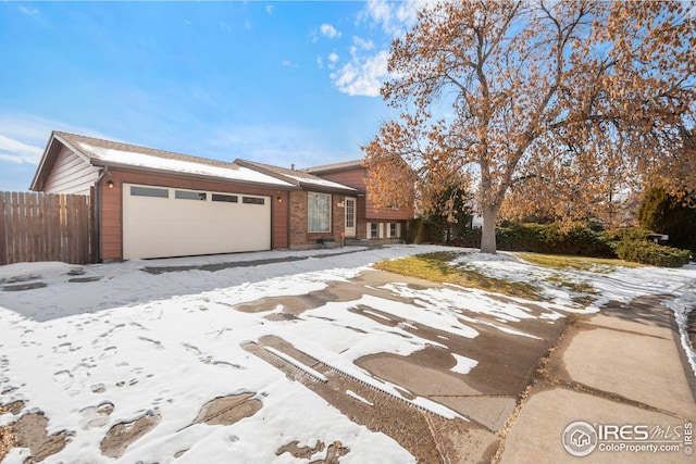 view of front of home with a garage, brick siding, and fence