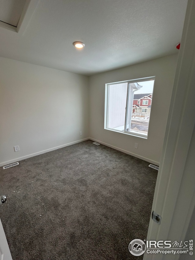 unfurnished room with baseboards, visible vents, and dark colored carpet