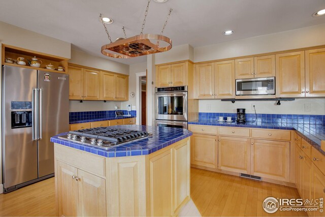 8400 Middle Fork Rd, Boulder, CO 80302 - kitchen featuring light brown cabinetry, tile counters, stainless steel appliances, and a center island
