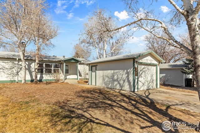 view of front of home featuring a garage, concrete driveway, and an outbuilding