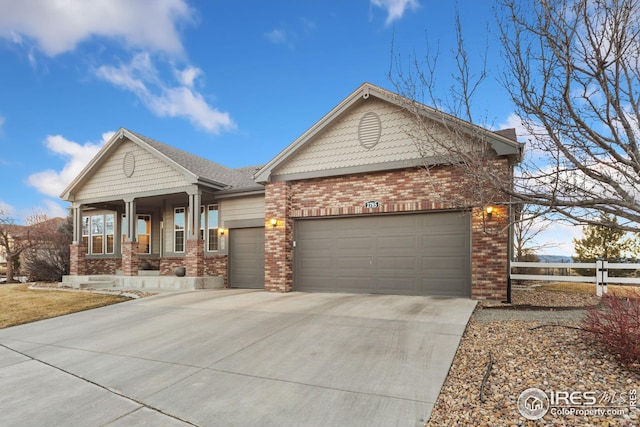 view of front facade featuring brick siding, a porch, an attached garage, fence, and driveway