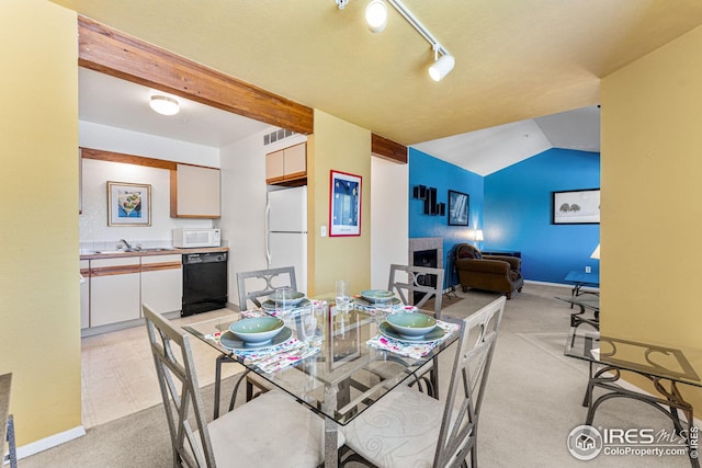 dining area featuring baseboards, light carpet, vaulted ceiling with beams, and track lighting