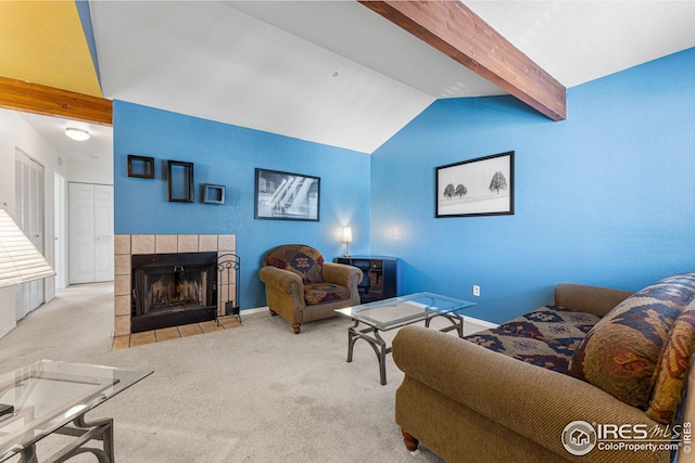 living area featuring carpet floors, vaulted ceiling with beams, baseboards, and a tile fireplace