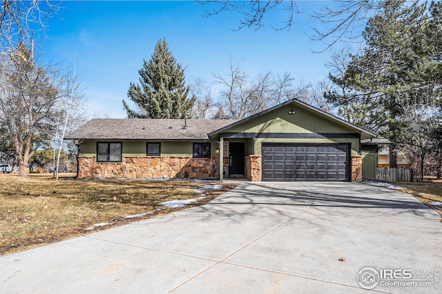 ranch-style house with stone siding, an attached garage, driveway, and a front yard