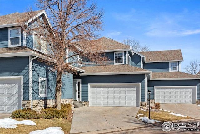 view of front facade with a garage, stone siding, driveway, and a shingled roof