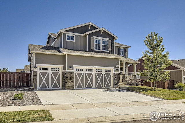craftsman-style home featuring concrete driveway, stone siding, an attached garage, fence, and board and batten siding