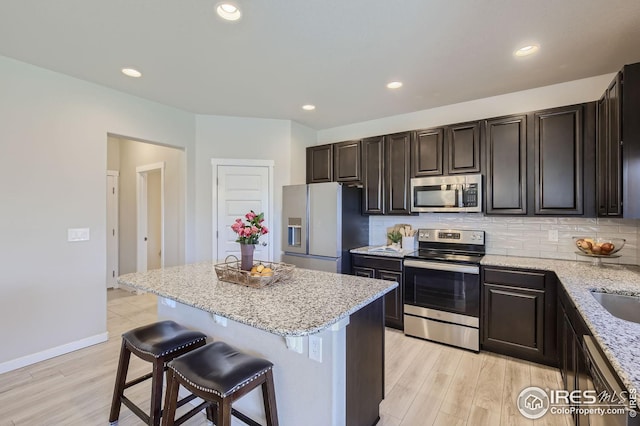kitchen featuring appliances with stainless steel finishes, a breakfast bar area, a kitchen island, and decorative backsplash