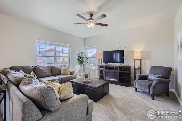 living area with light carpet, ceiling fan, and baseboards