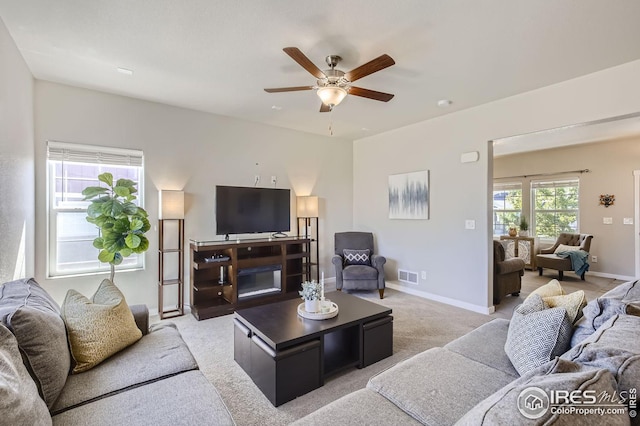 living room with light carpet, a ceiling fan, visible vents, and baseboards