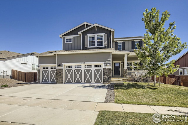 craftsman-style house featuring a garage, fence, concrete driveway, a front lawn, and board and batten siding