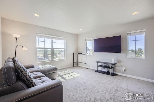living area with recessed lighting, light carpet, a textured ceiling, and baseboards
