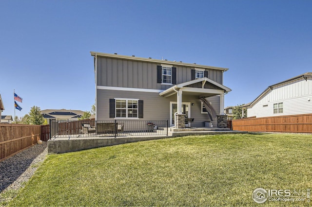 rear view of property with board and batten siding, a patio area, a fenced backyard, and a lawn