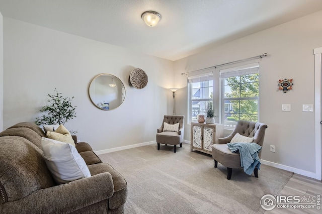 living area featuring light carpet and baseboards