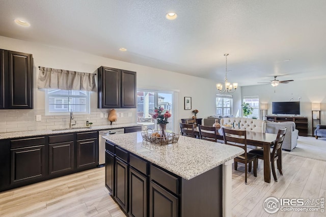 kitchen featuring a center island, hanging light fixtures, open floor plan, a sink, and dishwasher