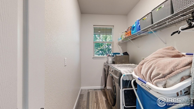 laundry room with a textured wall, wood finished floors, washer and dryer, laundry area, and baseboards