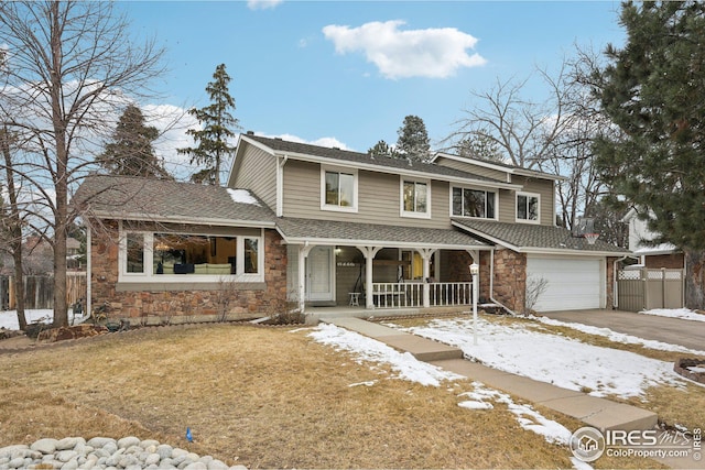 view of front of home with covered porch, a shingled roof, fence, stone siding, and driveway