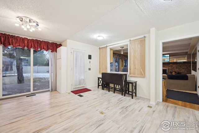 interior space featuring a textured ceiling, a barn door, wood finished floors, and baseboards