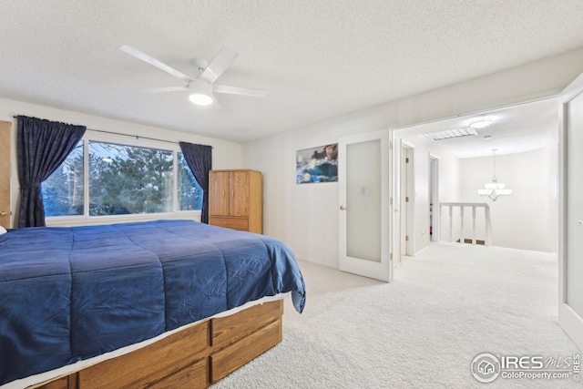 carpeted bedroom featuring a textured ceiling and ceiling fan with notable chandelier