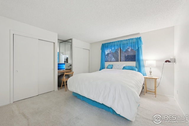 bedroom with a textured ceiling, multiple closets, and carpet flooring