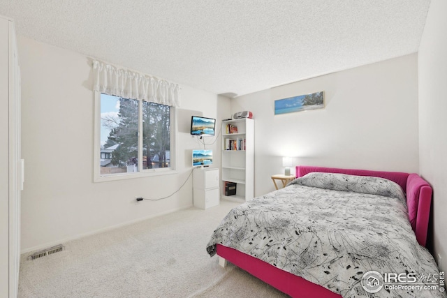 bedroom with carpet floors, visible vents, and a textured ceiling