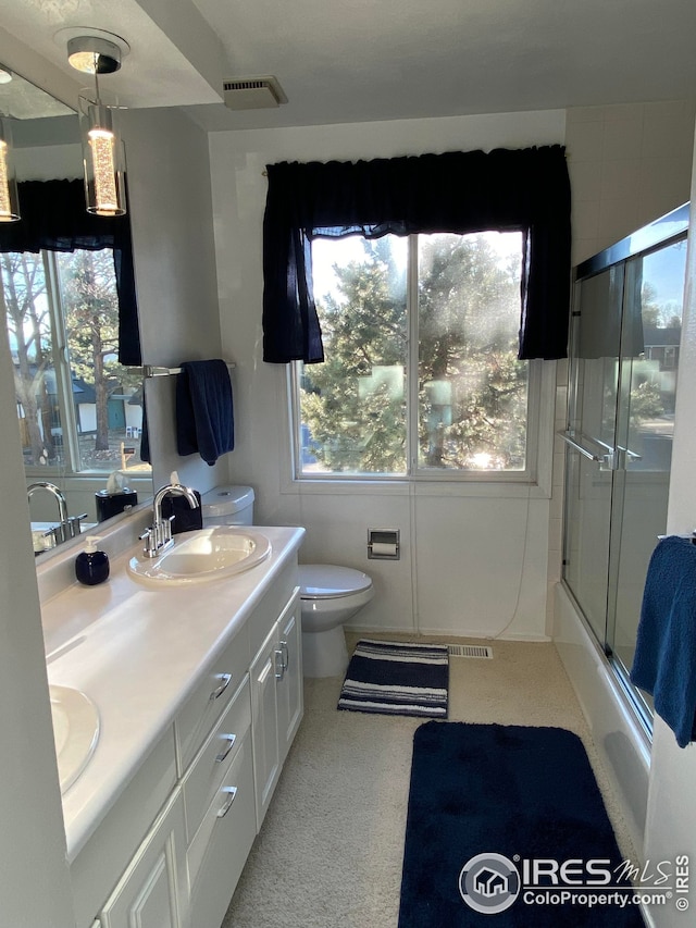 full bath with toilet, double vanity, visible vents, and a sink