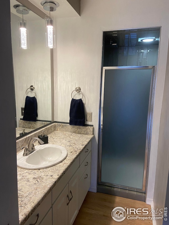 full bathroom featuring a stall shower, wood finished floors, and vanity