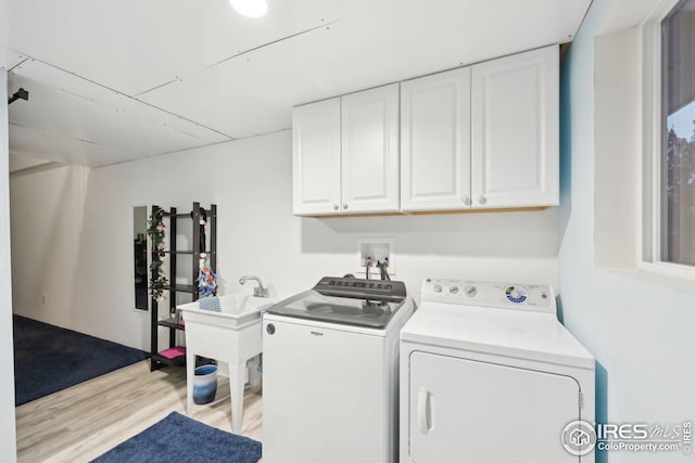 laundry room with washer and clothes dryer, light wood-type flooring, and cabinet space