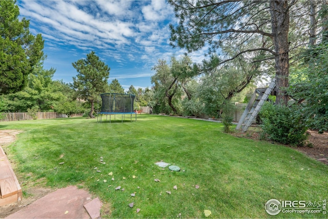 view of yard featuring a trampoline and fence