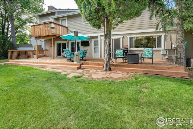 rear view of house with outdoor dining space, a chimney, a lawn, and a deck